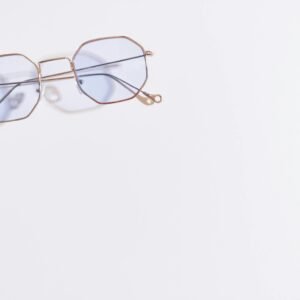 Close-up of hexagonal eyeglasses with blue tint on a white background, minimalistic style.