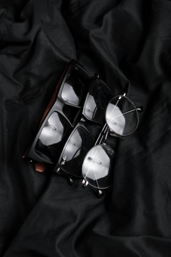 Close-up of various stylish eyeglasses on black fabric, highlighting modern eyewear design.