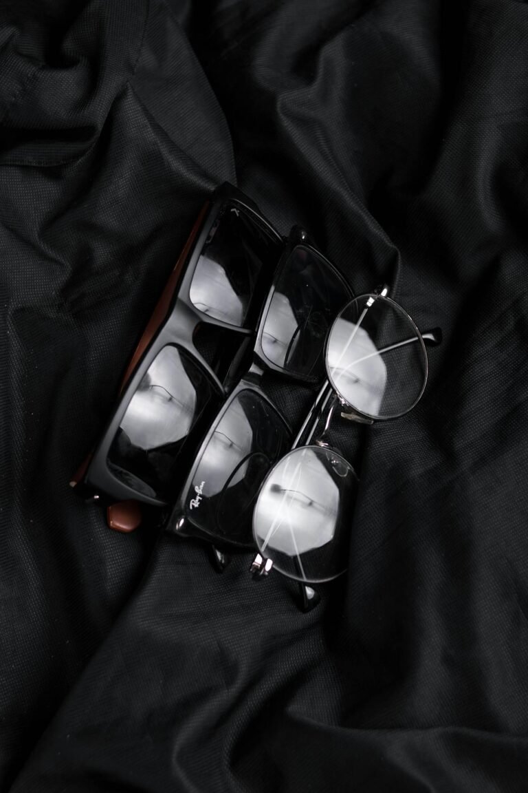 Close-up of various stylish eyeglasses on black fabric, highlighting modern eyewear design.
