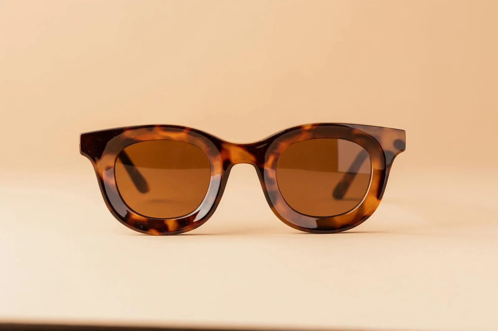 Stylish tortoiseshell sunglasses on a beige backdrop. Perfect for summer fashion.